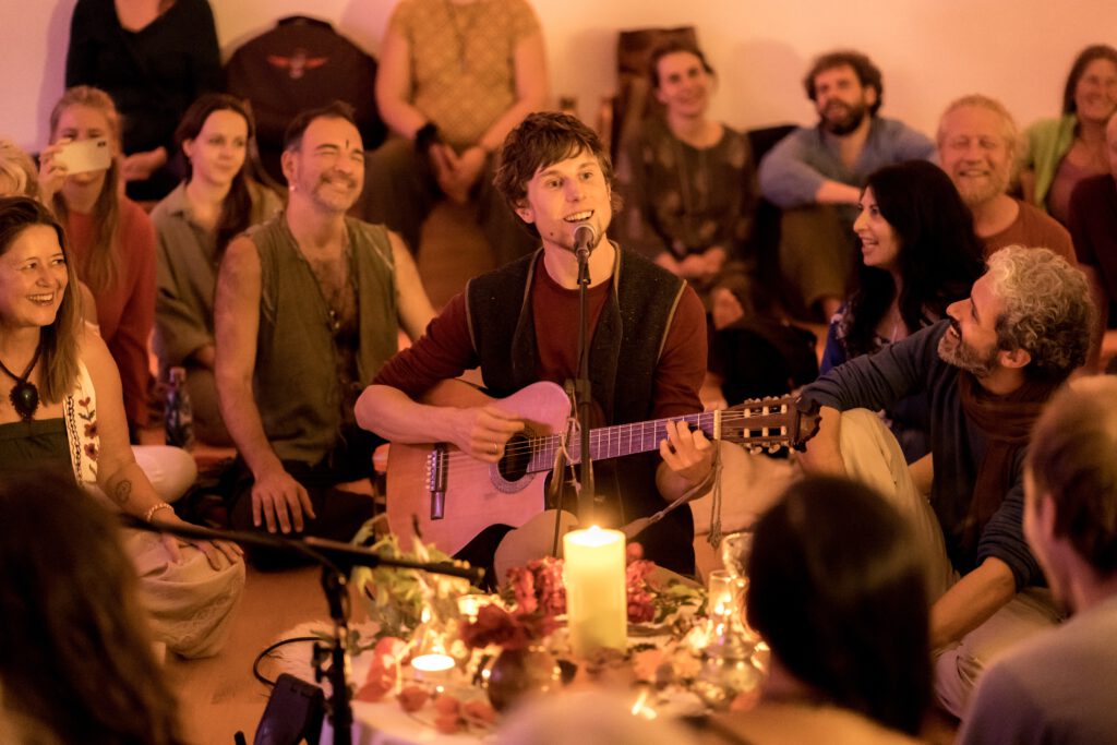 Florian Michael Litzlfelder bei einem Singing Circle mit Gitarre und singenden Menschen im Kreis