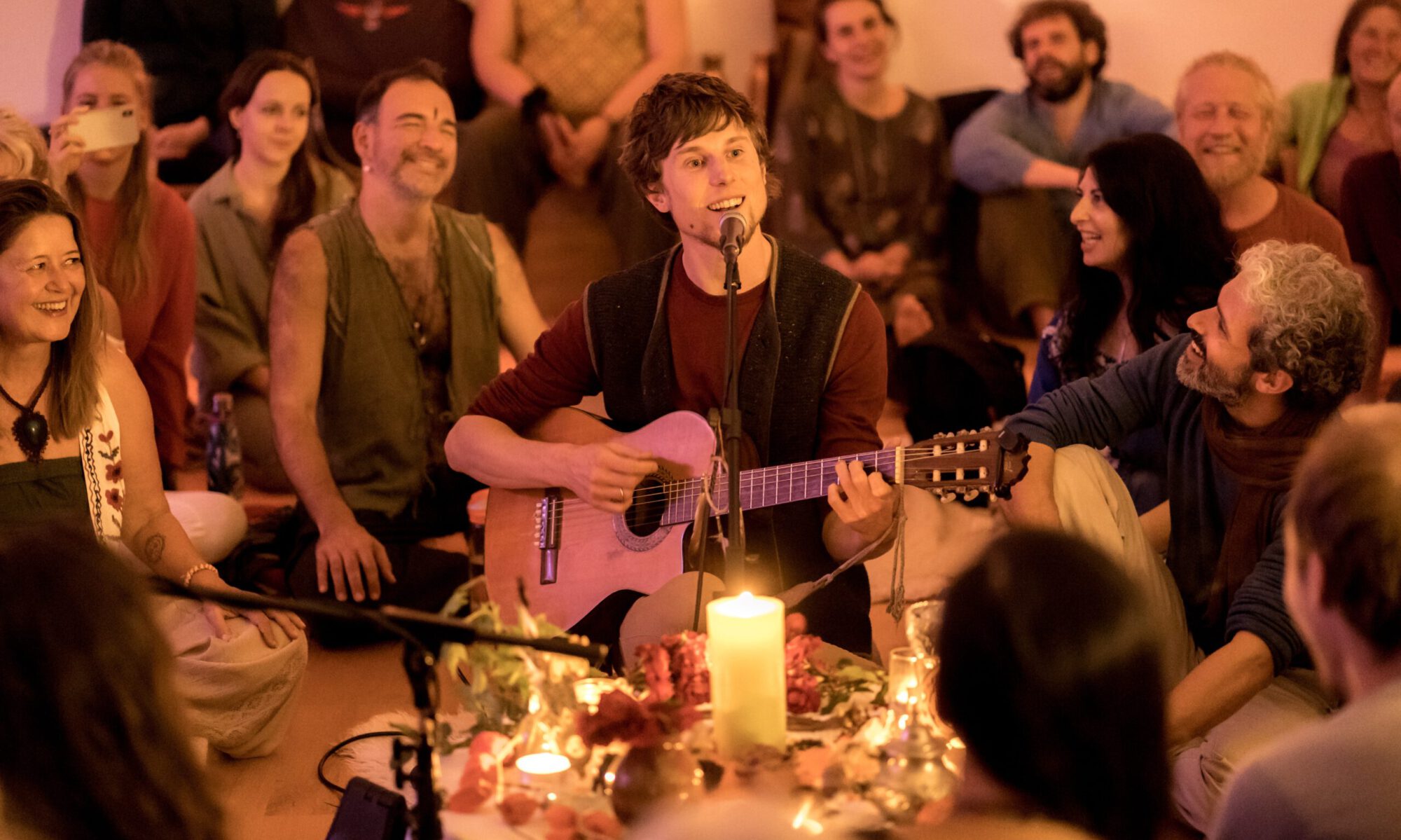 Florian Michael Litzlfelder bei einem Singing Circle mit Gitarre und singenden Menschen im Kreis